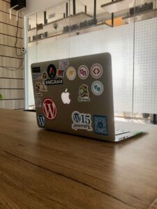 Laptop open on a table, its lid covered in WordPress stickers.